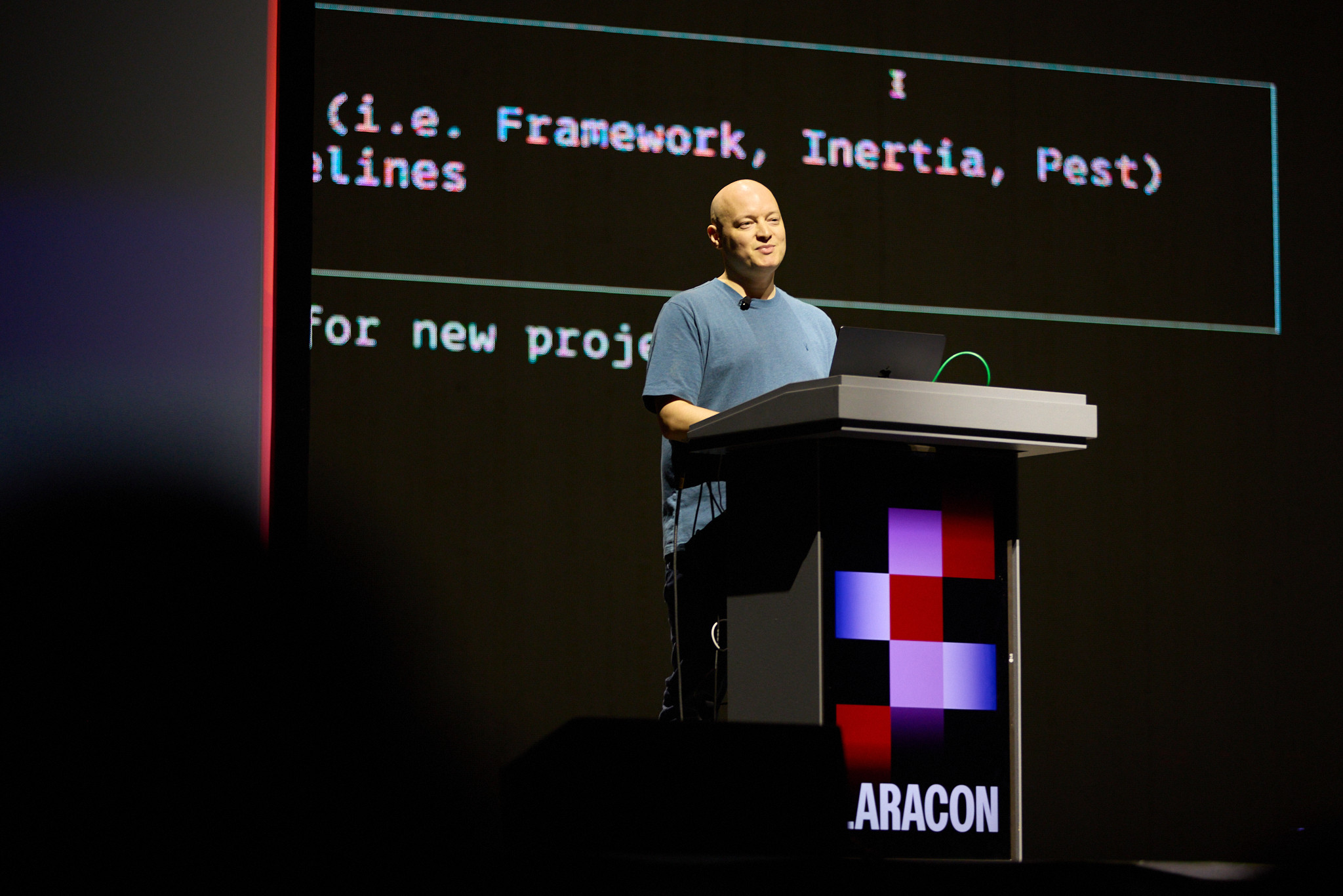 Ashley speaking at a lectern on a conference stage.